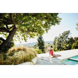 Umělecká fotografie Woman performing yoga on pool deck of home, Thomas Barwick, (40 x 26.7 cm)