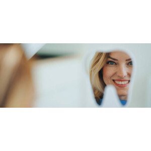Umělecká fotografie Happy patient looking at her teeth in mirror., Halfpoint Images, (50 x 21.4 cm)